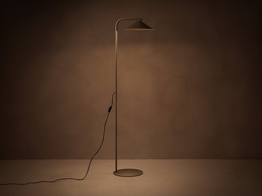 V tme rozsvietená stojanová lampa Nocte s tienidlom v tvare kužela, z kvalitného matne lakovaného kovu hnedej farby.
