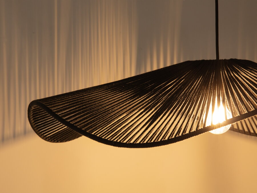 Svietiaca čierna závesná lampa v prítmí.