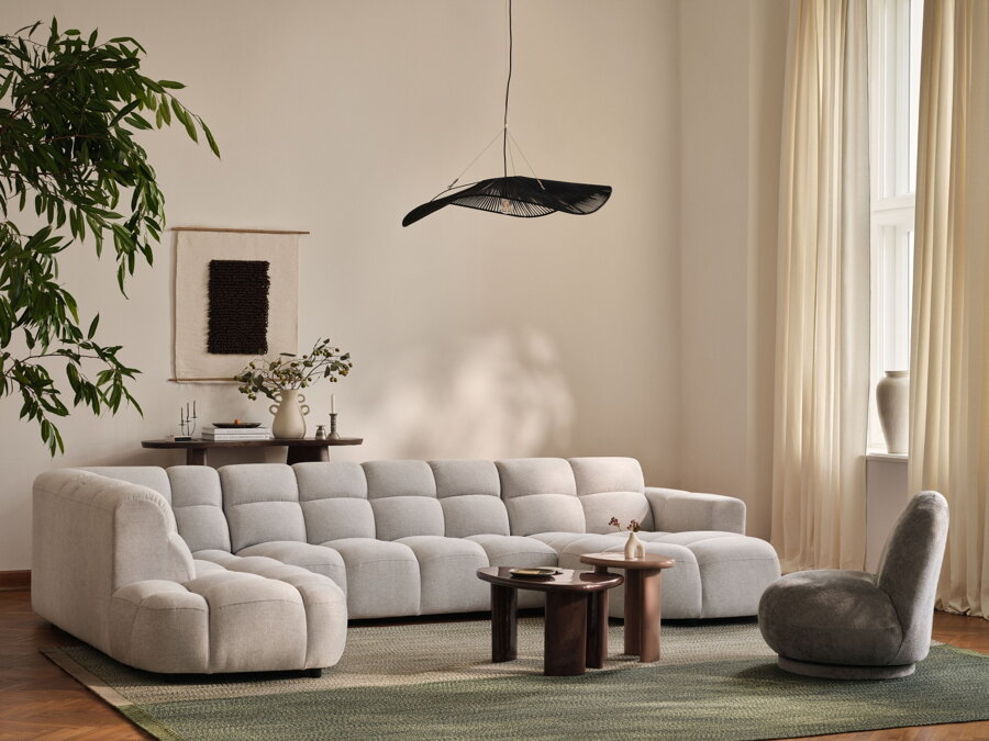 Čierna závesná lampa v obývačke s bielou sedačkou, sivým kreslom a konferenčným stolíkom.