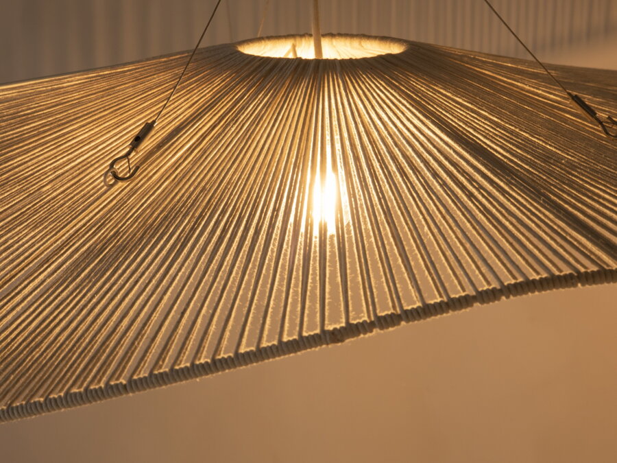 Svietiaca biela závesná lampa v prítmí.