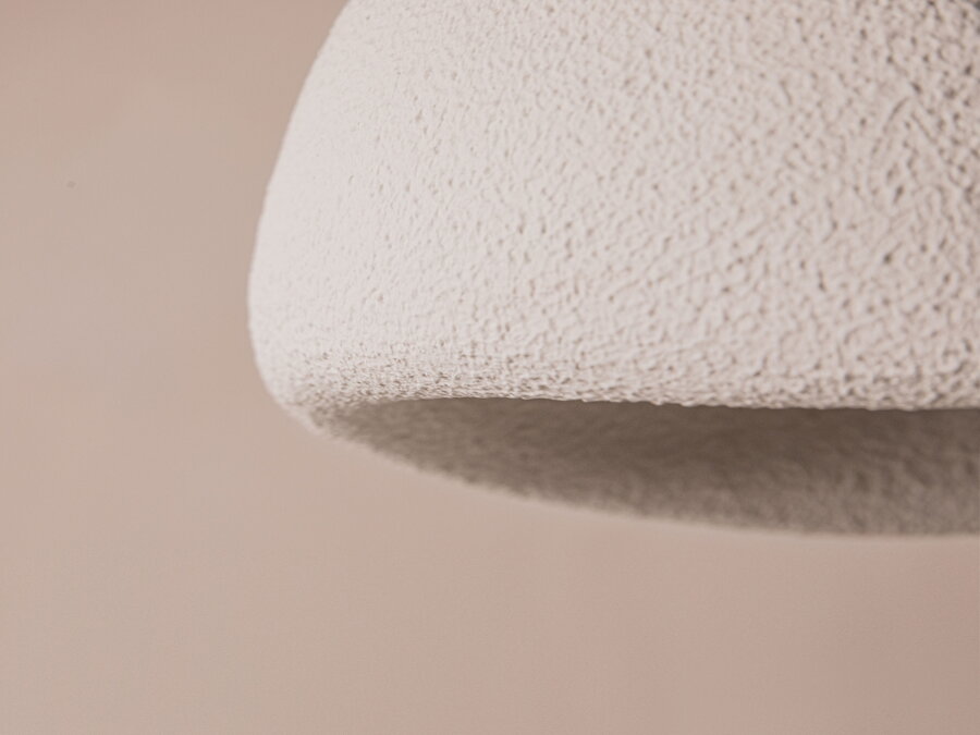 Detailný pohľad na mikrocementovú povrchovú úpravu bieleho tienidla lampy.