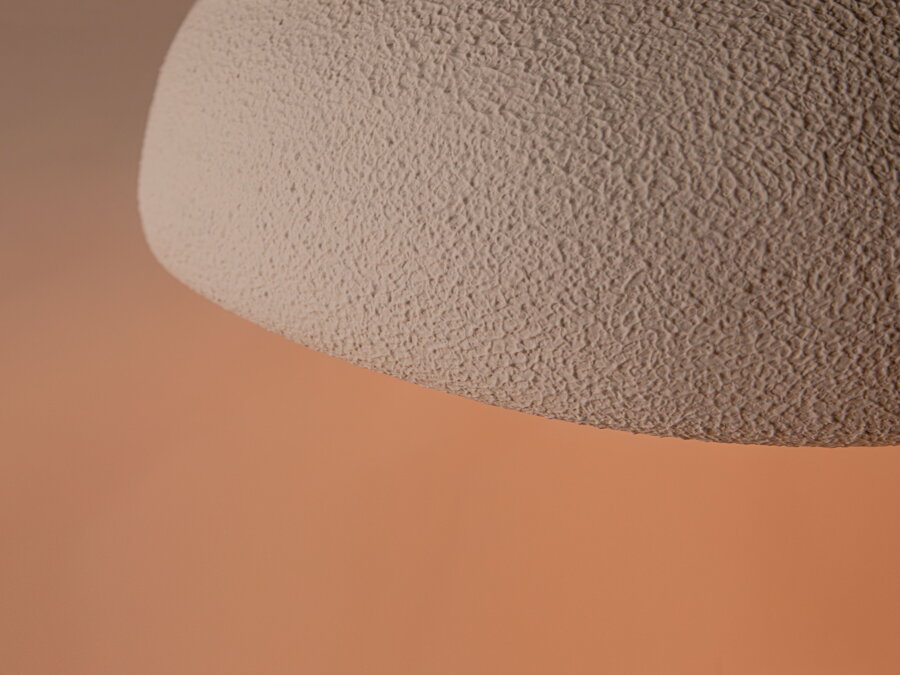 Detailný pohľad na mikrocementovú povrchovú úpravu bieleho tienidla lampy.