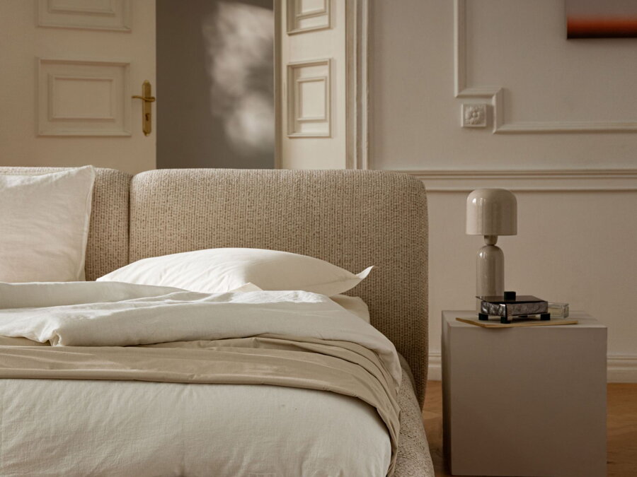 Detail na čelo ustlanej manželskej postele Solange v čalúnení béžovej farby v spálni.