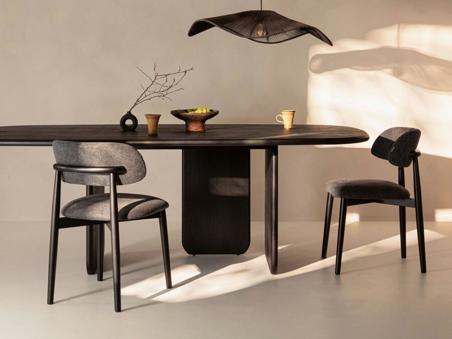 Čierny jedálenský stôl s dvoma jedálenskými stoličkami v miestnosti s čiernym lustrom.