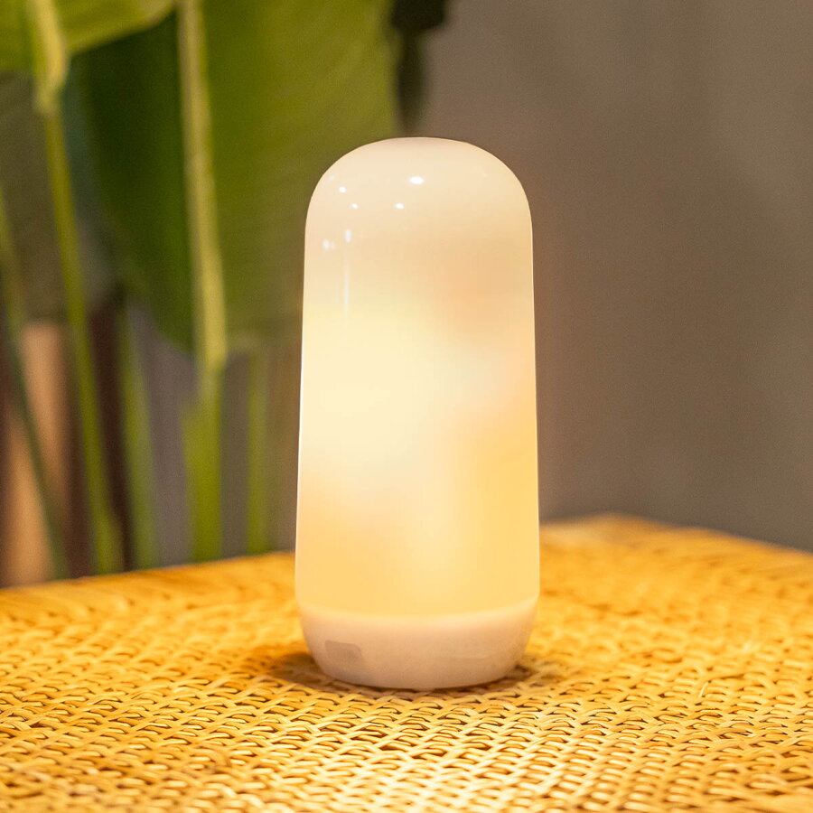 Bezdrôtová lampa so svetlom s efektom plameňa položená na ratanovom stolíku