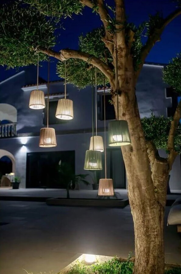 Mini závesné lampy svietiace na konároch stromu vo večernej atmosfére