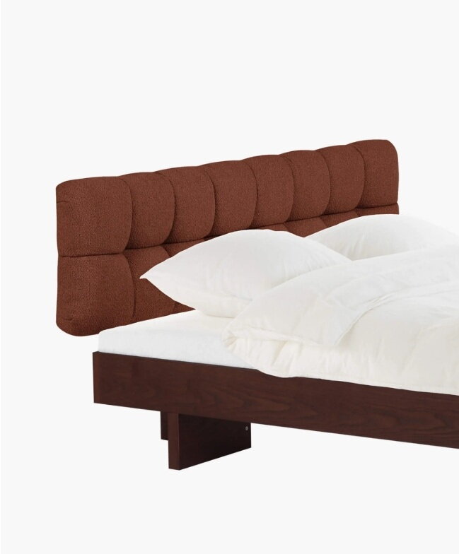 Drevená manželská posteľ s čalúneným čelom tehlovej farby.