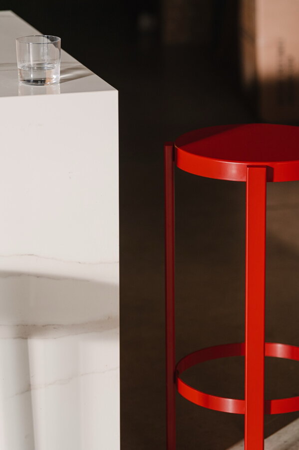 Dve červené barové stoličky pri barovom pulte.