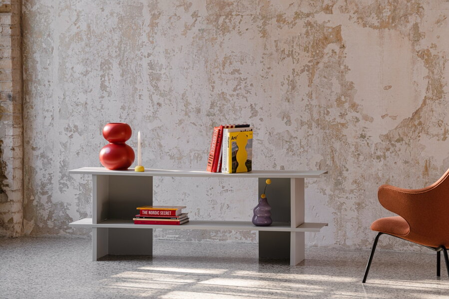 Sivá kovová polica v miestnosti s červeným kreslom.