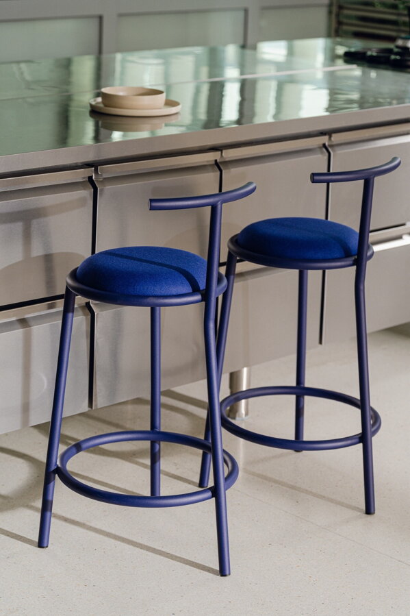 Dve modré barové stoličky s opierkou pred kuchynským ostrovčekom.