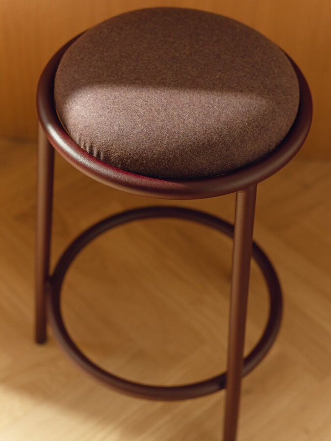 Barová stolička Hogo s čalúneným sedákom a oceľovým rámom v bordovej farbe.