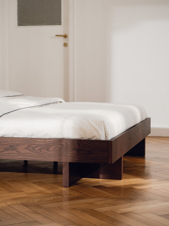 Tmavohnedá drevená posteľ v spálni.