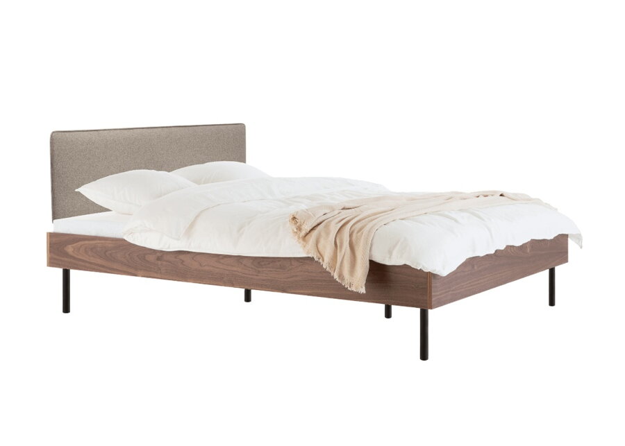 Posteľ Streiko z orechovej dyhy prírodnej farby s čalúneným čalom v odtieni kávovo hnedom.