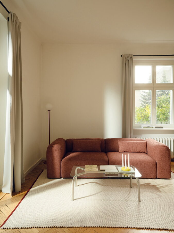 3-miestna pohovka tehlovej farby v obývačke na béžovom koberci.