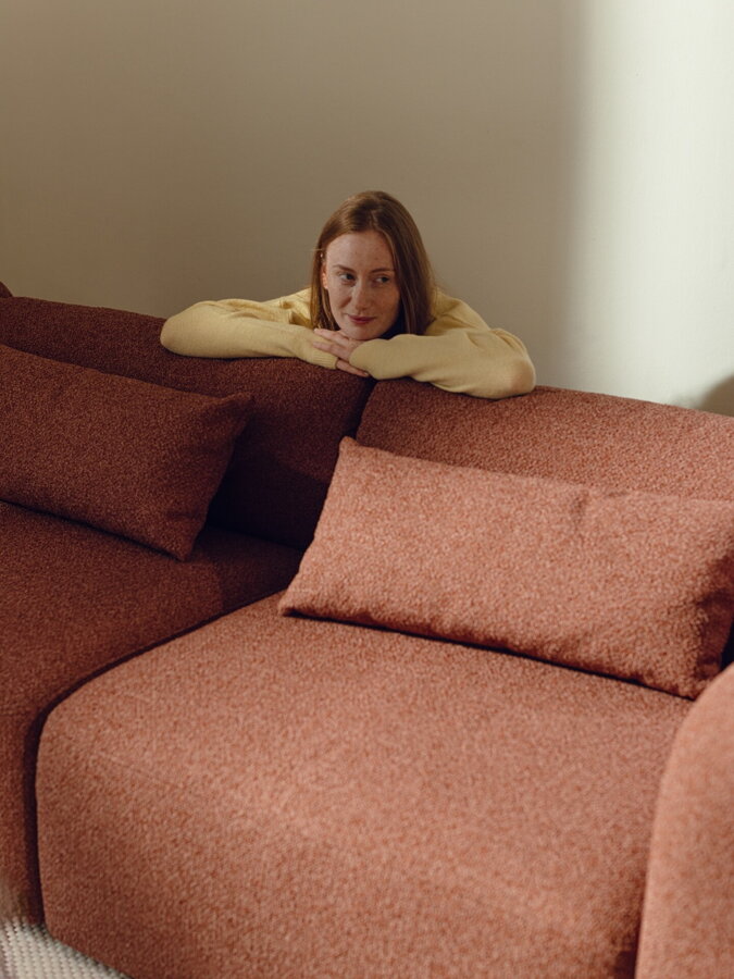 Žena opierajúca sa zozadu o chrbtovú opierku pohovky.