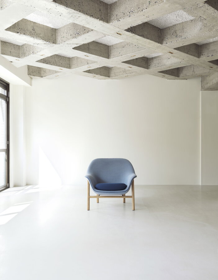 Modré čalúnené kreslo Drape Lounge Chair uprostred veľkej svetlej miestnosti.