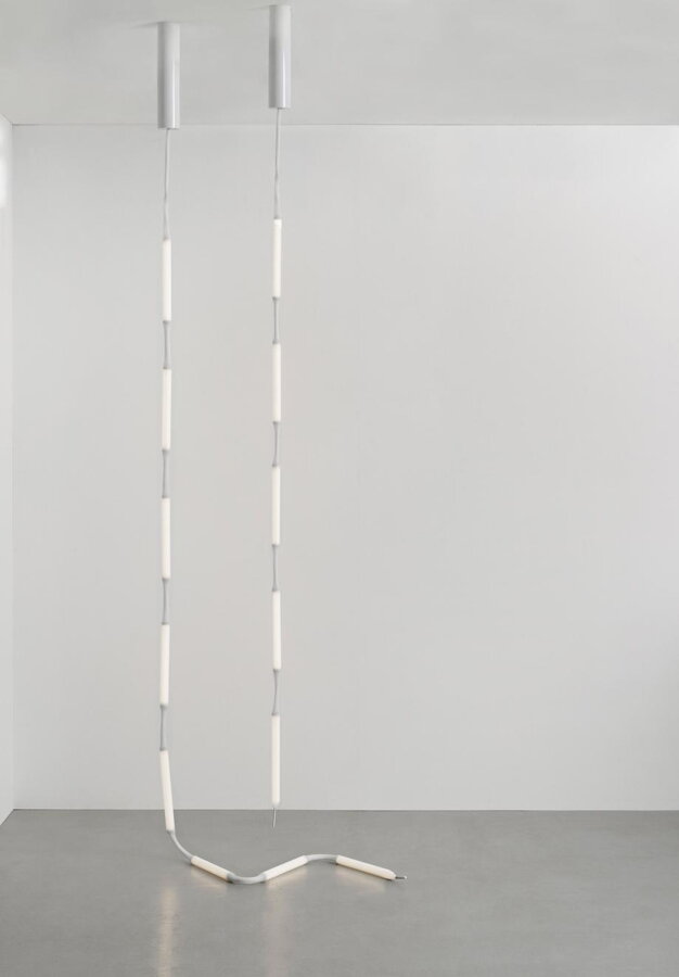 Lampa Reb s 5 aj 8 svetelnými modulmi visiaca voľne z bieleho stropu, dopadajúca na sivú podlahu.