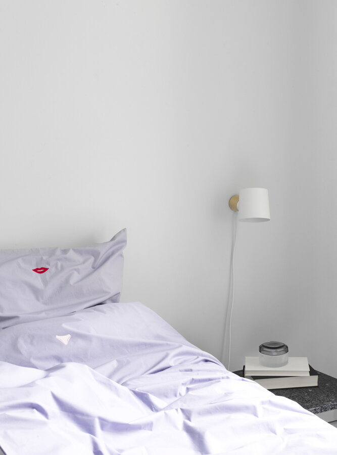 Štýlová biela nástenná lampa s dreveným podstavcom ako nočná lampa v spálni