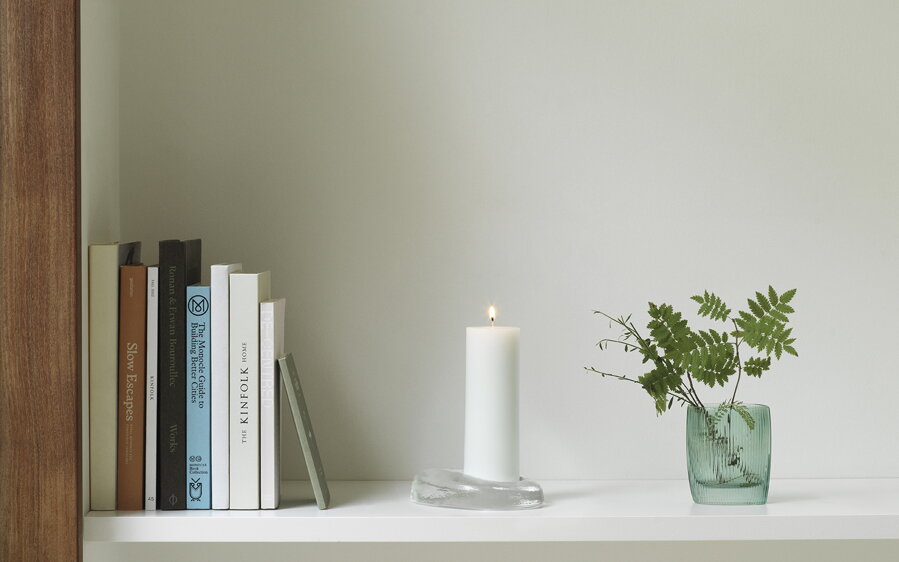 Svietnik Odd umiestnený na bielej polici vedľa kníh.