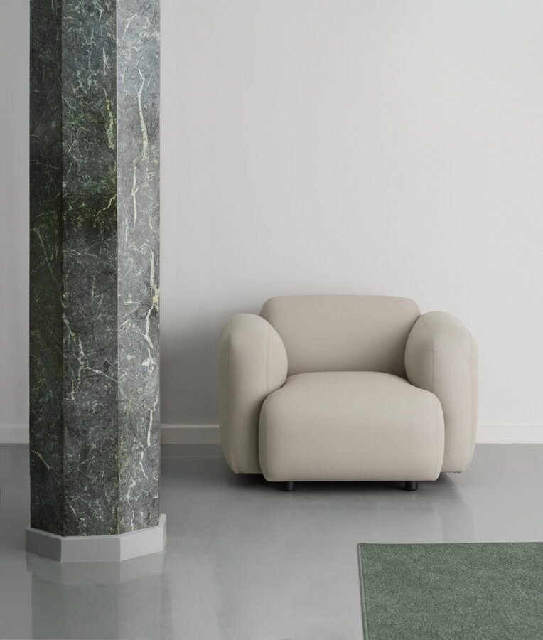 Béžové kreslo Swell Armchair pri stene pri sivom mramorovom stĺpe.