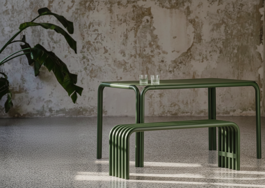 Kovová lavica a stôl zelenej farby v miestnosti s mramorovou podlahou a stenou a s izbovou rastlinou.